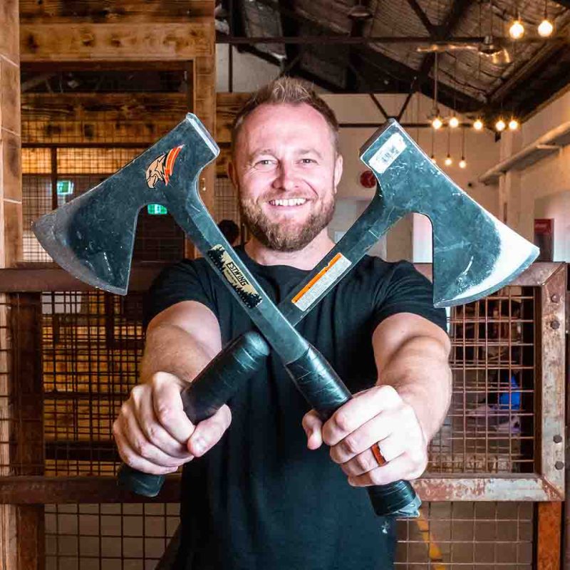 guy holding up two axes crossed at the middle blades pointing out