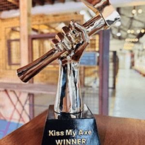 Silver trophy with an axe and 'Kiss My Axe WINNER' text on a wooden base.