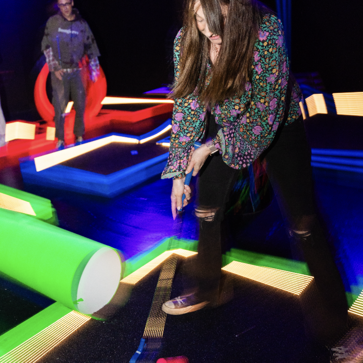 girl putting a glow in the dark golf ball into the hole