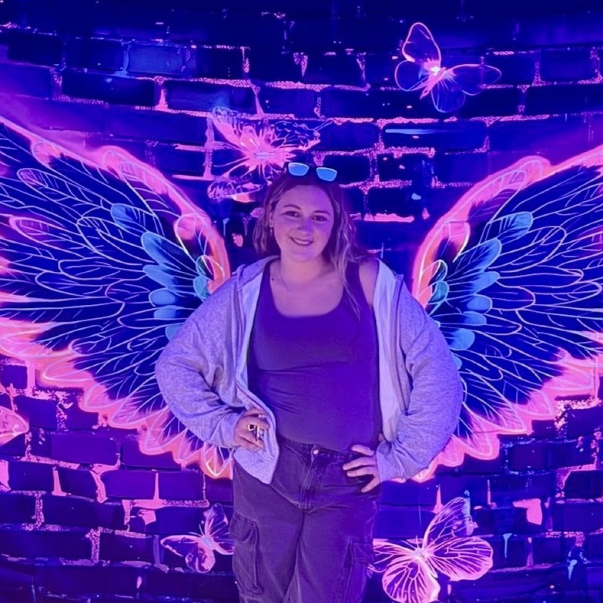 woman standing in front of neon feathered wings