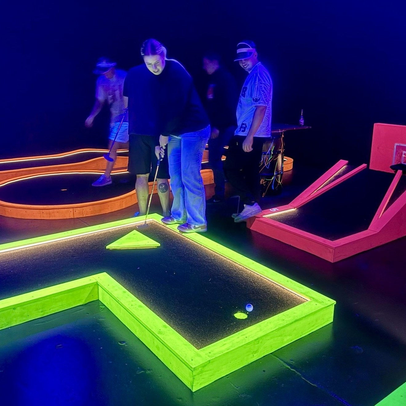 couple playing on neon mini golf course