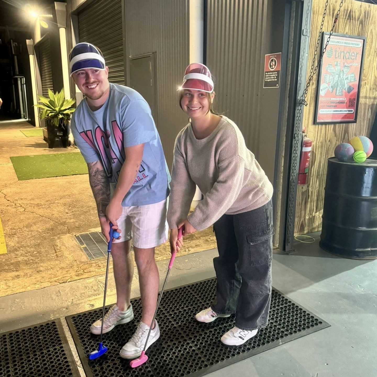couple practicing their mini golf putting techniques while wearing visors