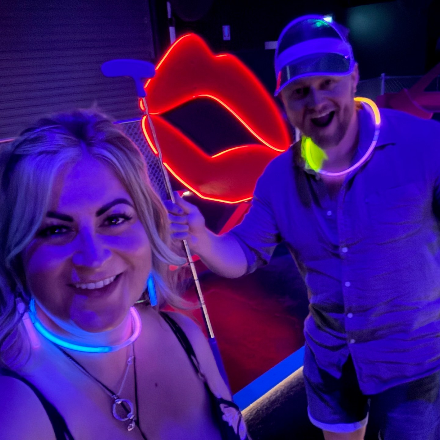 couple smiling in neon necklaces during glow in the dark mini golf