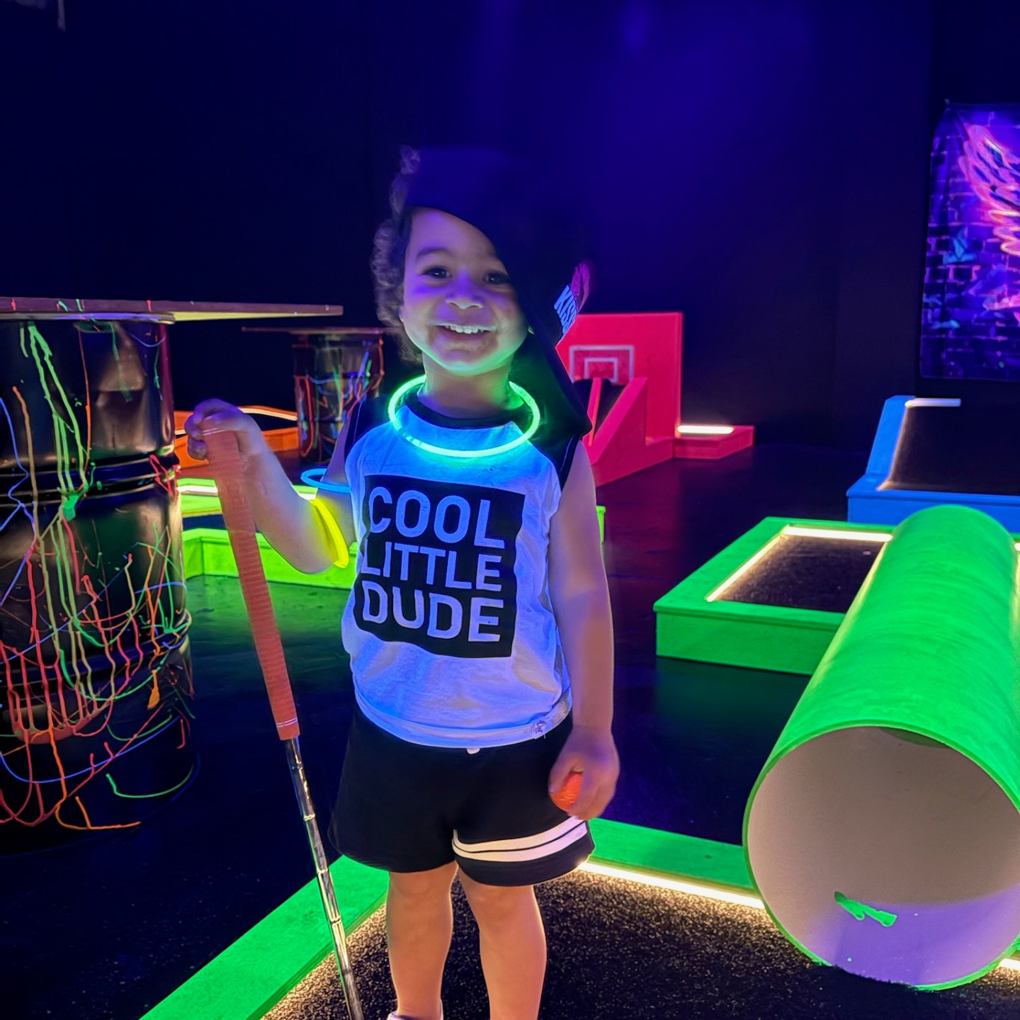 girl holding a putter for glow in the dark mini golf