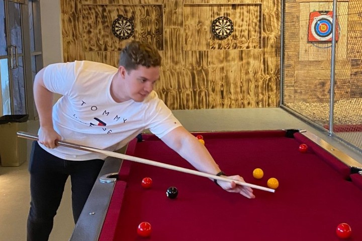 guy aiming to put a ball in a pocket of a pool table