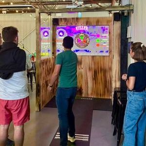 Four people playing an interactive game on screens in an indoor setting.