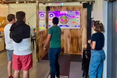 Four people playing an interactive game on screens in an indoor setting.