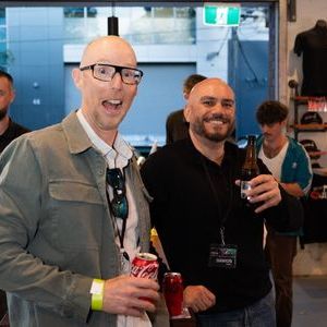 Two men smiling and holding drinks at a casual indoor gathering.