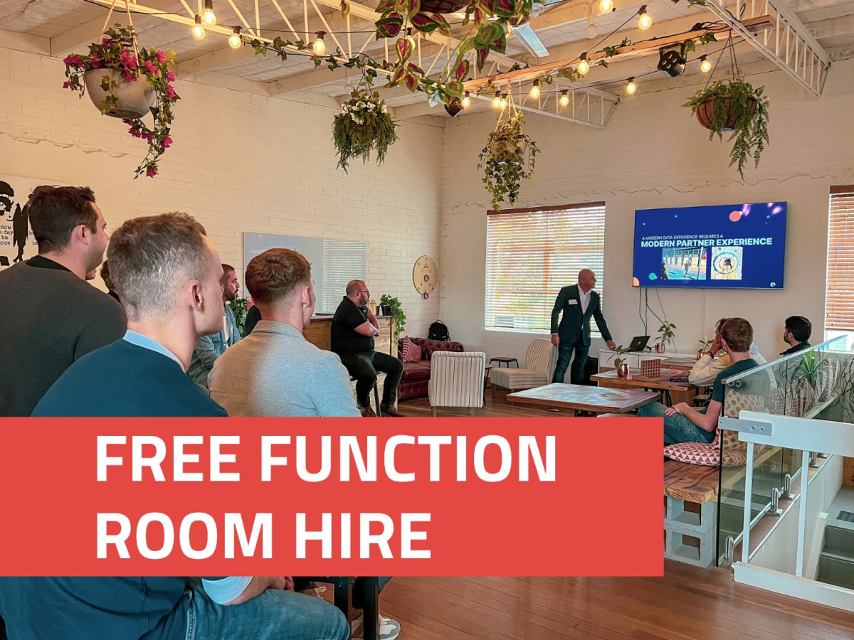 People in a function room watching a presentation, with a banner reading 'Free Function Room Hire'.