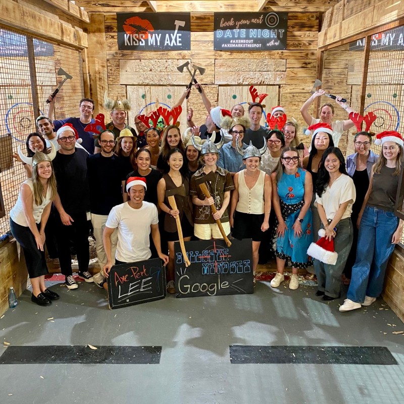 Group of people in festive hats and props at an axe throwing venue.