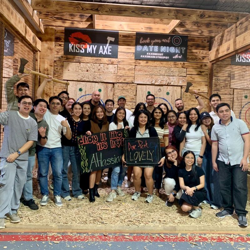 Group of people posing with signs in an axe-throwing venue.