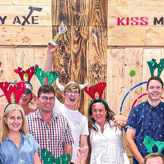 Group of people with reindeer antlers celebrating, holding a sign that reads 'Winner Mitch'.