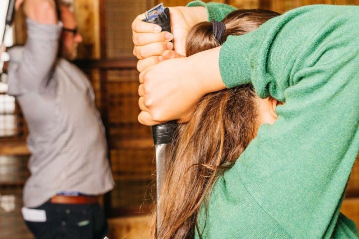 Two people preparing to throw axes in an indoor range.