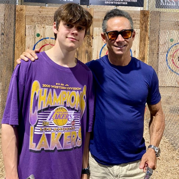 Two people at an axe throwing event, one holding an axe, standing in front of target boards.