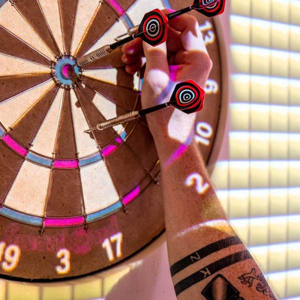 Tattooed arm reaching for darts on a dartboard.