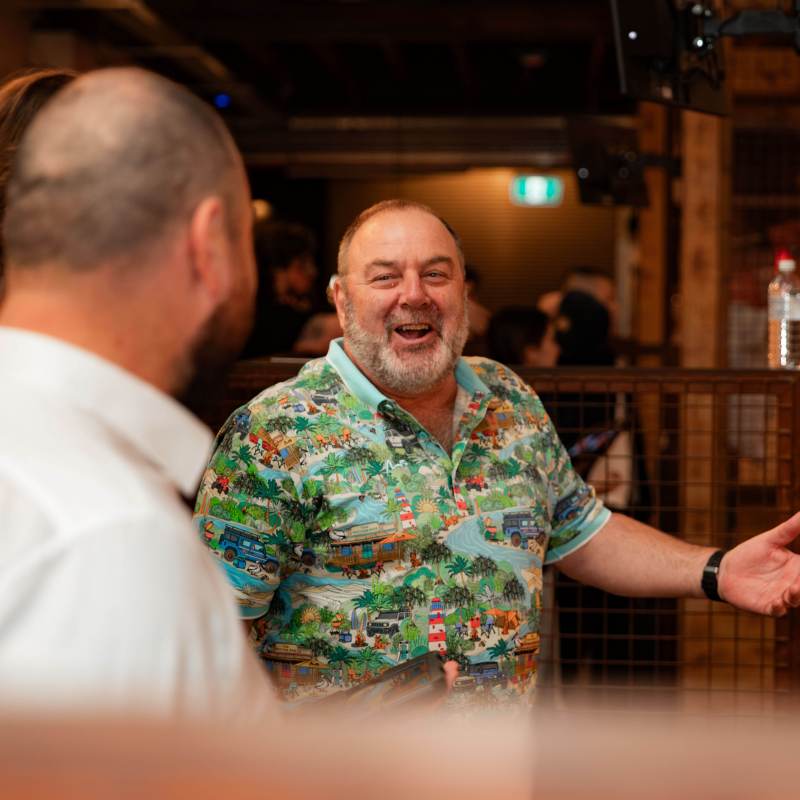 Man in colorful shirt laughing at a social gathering.