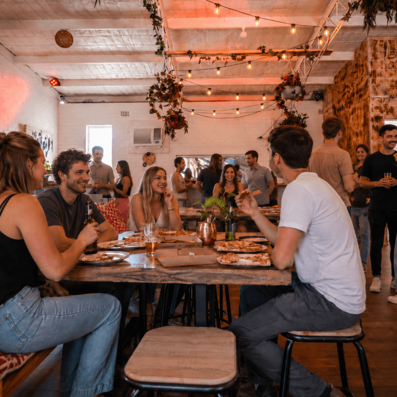 Group of people socializing at a casual indoor gathering with food and drinks.