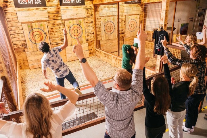 Group of people cheering at an indoor axe-throwing venue.