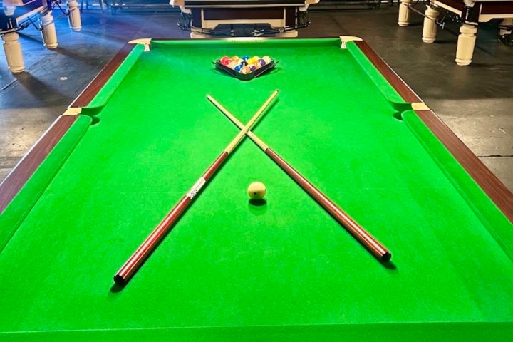 Pool table setup with cues crossed and a racked ball triangle.