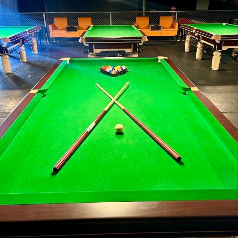 Pool table setup with cues crossed and a racked ball triangle.